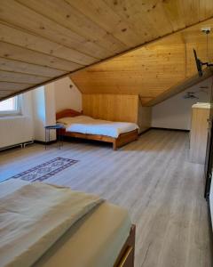 a attic room with two beds and a wooden ceiling at Pensiunea 7 Brazi II in Poiana Mărului