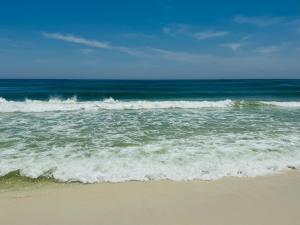 plaża z oceanem i falami w obiekcie Pensacola Beach Front Emerald Waters w mieście Pensacola Beach