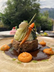 um pedaço de carne com vegetais num prato em L'Arcalod Hôtel Restaurant & Spa em Doussard