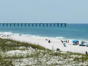 a group of people on a beach with a pier at Pensacola Beach Front Emerald Waters in Pensacola Beach