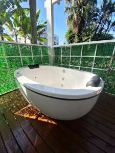 une baignoire blanche assise sur une terrasse en bois dans l'établissement Garden 437 Estúdios, à Florianópolis