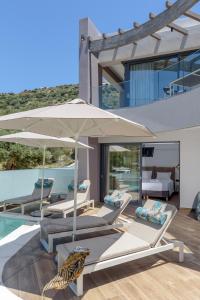 a villa with a swimming pool with chairs and an umbrella at Plakias Galaxy Villas in Plakias