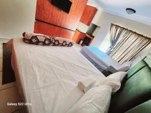 a bedroom with a bed and a couch and a window at WAMPEX GUEST HOUSE IN RUSTENBURG in Rustenburg