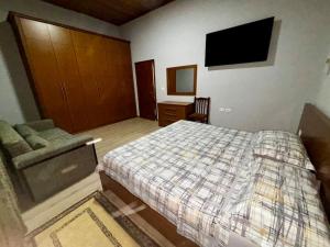 a bedroom with a bed and a couch and a television at Central 2 Floor, Duplex in Elbasan
