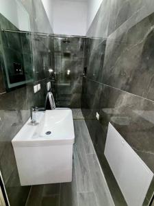 a bathroom with a white sink and a shower at Central 2 Floor, Duplex in Elbasan
