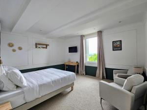 um quarto com uma cama, uma cadeira e uma janela em La Suite Gignac em Gignac