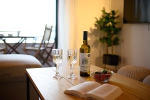 a bottle of wine and two glasses on a table at Corfu Glyfada Beach Apartment in Glyfada +22 photos