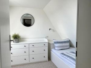 a bedroom with a white dresser and a mirror at Johannsen-Huis-Appartement-Dena in Tinnum