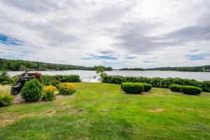 a grassy yard with bushes and a body of water at OCEAN BAY VIEW Luxury Guesthouse in Musquodoboit Harbour