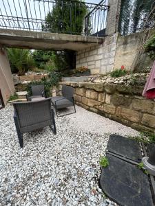 a patio with two chairs and a table and a stone wall at Le Belvédère + Clim + Extérieur + Parking Gratuit in Les Angles Gard