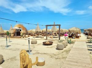 a sandy beach with chairs and umbrellas on the beach at Lamera - Alezzi Apartament langa mare cu acces la piscina, jacuzzi, sauna si sala de fitness in Năvodari