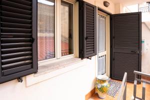 a window with black shutters and a vase on a porch at ALLEJANNI in Letojanni