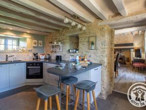 a kitchen with a counter and stools at Gîte charmant avec jardin, proche activités nautiques - FR-1-622-75 in Morannes