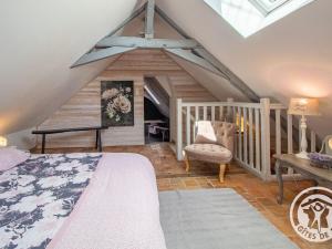 a attic bedroom with a bed and a chair at Gîte charmant avec jardin, proche activités nautiques - FR-1-622-75 in Morannes