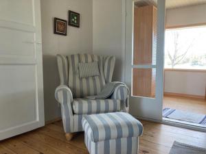 a living room with a chair and a stool at Naantalissa idyllinen merenrantatalo, OnnenPoukama in Naantali +30 photos