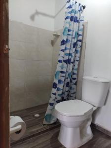 a bathroom with a toilet and a shower curtain at Cabaña Buenos Aires in Palomino
