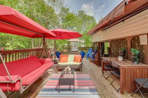 Una terraza con un sofá rojo, sillas y sombrillas. en Long Pond Home with Hot Tub about 8 Mi to Kalahari!, en Long Pond