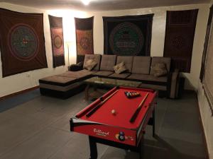 uma sala de estar com um sofá e uma mesa de bilhar vermelha em Intihuatana Hostel em Písac