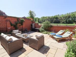 eine Terrasse mit Korbmöbeln und Ziegelwand in der Unterkunft The Smithy in Grimsby