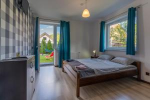 a bedroom with a bed with blue curtains and a window at Pokoje Goscinne AnMar in Krościenko