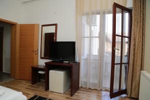 a living room with a television on a table with a mirror at Hotel Venisi in Prizren