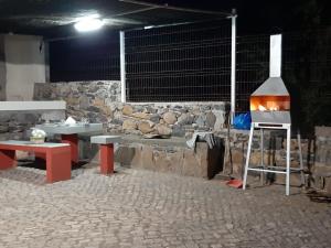 ein Zimmer mit einem Grill, Tischen und einer Steinmauer in der Unterkunft Pensione Casa da AMIZADE B&B in Pedra Badejo