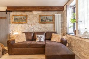 un divano marrone in un soggiorno con parete in pietra di Centro Storico Sestola Wifi e Netflix a Sestola