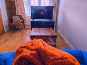 a living room with a couch and a tv with a blanket at Private Parking & Pillow Paradice With RR Housing in Leamington Spa