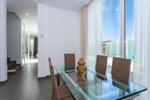a dining room with a glass table and chairs at Casa Daniela Lanzarote piscina climatizada, barbacoa y wifi free in Tahiche