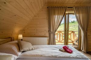 a bed in a wooden room with a large window at DOMKI Szarotka, Rozeta i Parzenica in Ratułów