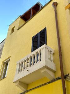 a yellow building with a white balcony on it at Casa Thamay in Brindisi