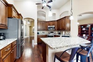 a kitchen with wooden cabinets and a kitchen island with bar stools at Cardinal Comfort in Litchfield Park
