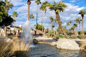 a fountain in a park with palm trees at Cardinal Comfort in Litchfield Park