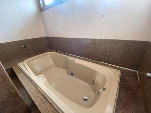La salle de bains est pourvue d'une baignoire blanche et d'un mur en carrelage. dans l'établissement Pousada Wafeh Pampulha Suítes, à Belo Horizonte