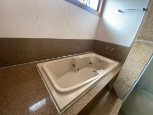 uma banheira na casa de banho com uma bancada em Pousada Wafeh Pampulha Suítes em Belo Horizonte