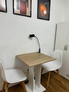 a table with two white chairs and a lamp on it at chambre d'hote in Issy-les-Moulineaux
