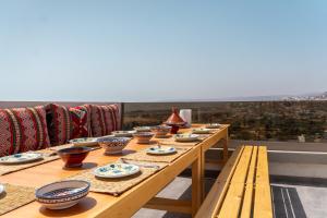 a long wooden table with bowls and plates on at Tayyurt Surf Camp Tamraght Aourir in Imi Mikki