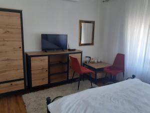 een slaapkamer met een bed en een bureau met een televisie bij Apartmani Zaara in Sarajevo