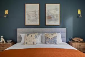 Un dormitorio con una cama con tres cuadros en la pared. en The Coyote, en Saugatuck