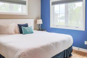a bedroom with a white bed and two windows at Lost Lake Lodge in Nisswa