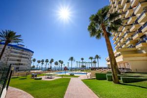 a resort with a pool and palm trees and a building at Benalmádena Living in Benalmádena