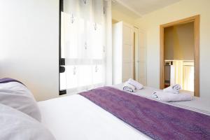 a white bedroom with a bed with towels on it at Benalmádena Living in Benalmádena +14 photos