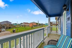 eine Veranda mit 2 Stühlen und Blick auf eine Straße in der Unterkunft Deep Blue Yonder - Ping-pong! Bikes! Games! Cute and cozy 3-bed, 2-bath home in the heart of Crystal Beach! in Crystal Beach