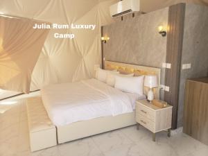 a bedroom with a white bed and a night stand at Julia Rum Luxury Camp in Wadi Rum