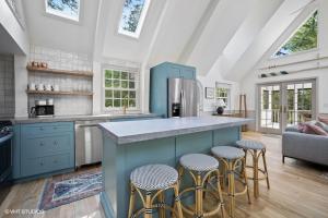 a kitchen with a blue island with stools at The Songbird in New Buffalo