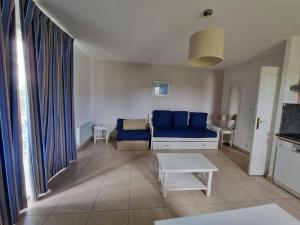 a living room with a blue couch and a table at B08 1er etage La Ferme de Deauville 1 ch SOZEN C in Saint-Arnoult