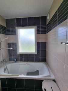 a bathroom with a bath tub and a window at B08 1er etage La Ferme de Deauville 1 ch SOZEN C in Saint-Arnoult