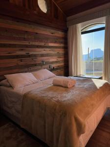 1 dormitorio con 1 cama con pared de madera en Pousada Chalés Por do Sol en Campos do Jordão