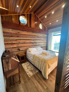 ein Schlafzimmer mit einem Bett und einer Holzwand in der Unterkunft Pousada Chalés Por do Sol in Campos do Jordão