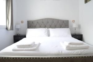 a white bed with two white towels on it at Casa en alquiler vacacional en Alcalá de Henares in Alcalá de Henares